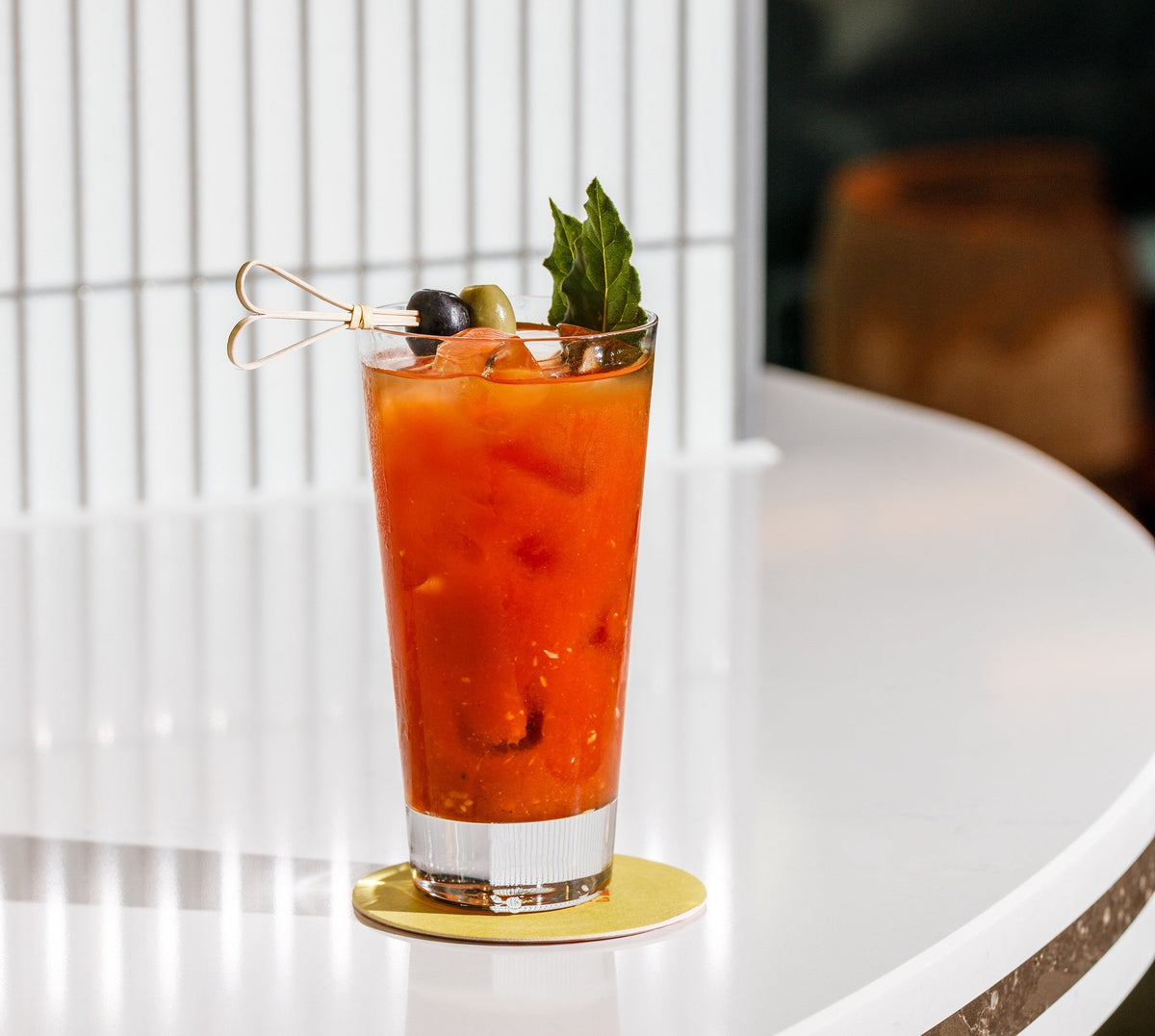 A bloody mary in a tall glass on a white table