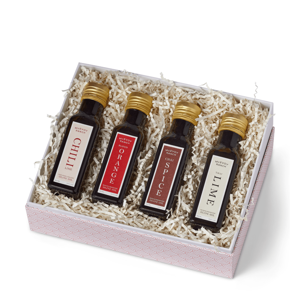 Set of four miniature bottles with gold caps in a decorative box on a white background